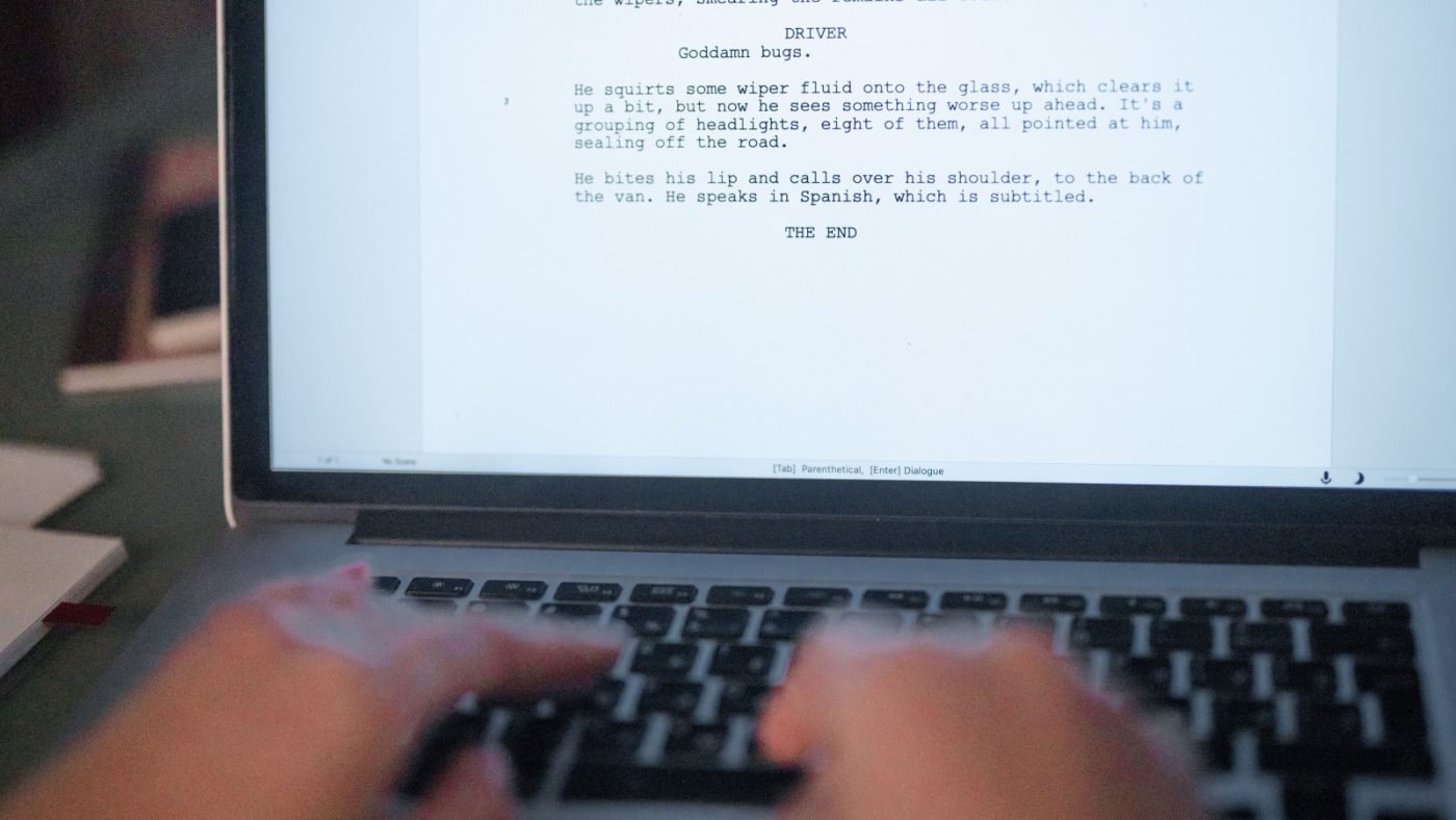 Hands editing a written draft on a laptop keyboard