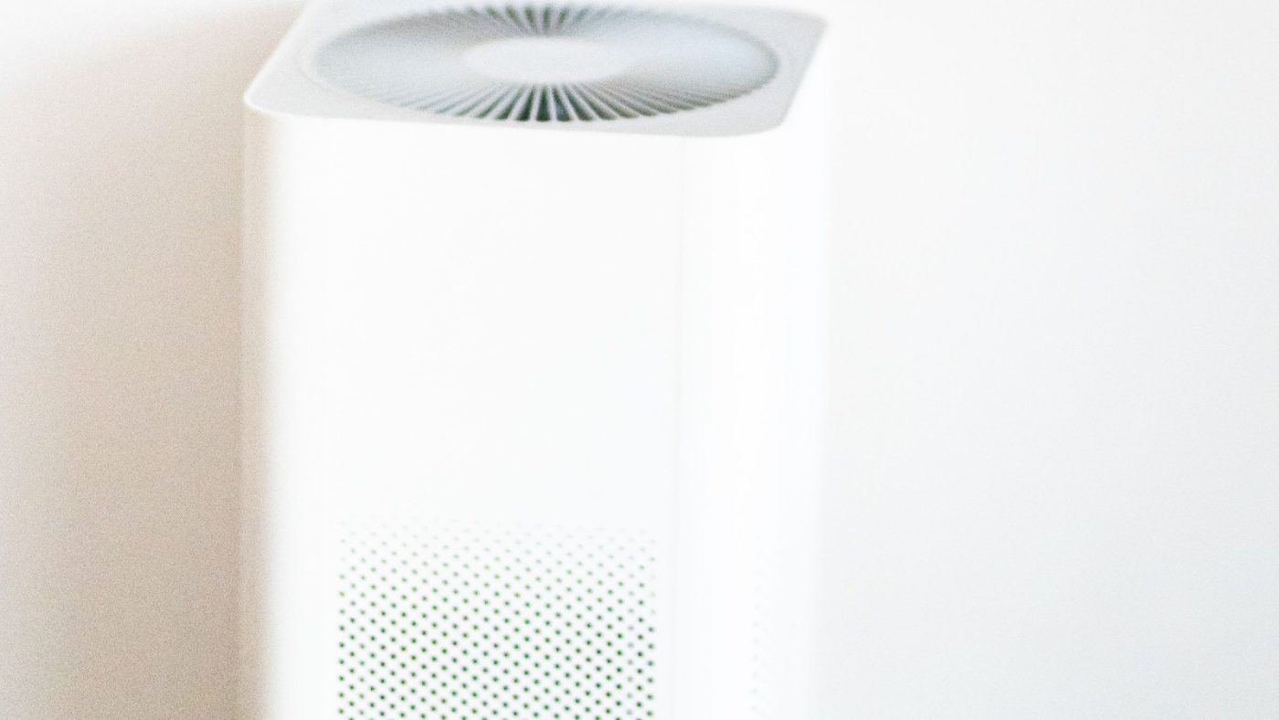 A white tower air purifier running in a bright room